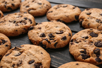 Tasty cookies with chocolate chips on dark wooden table