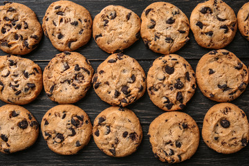 Tasty cookies with chocolate chips on dark wooden table
