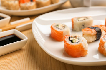 Plate with tasty sushi on wooden table
