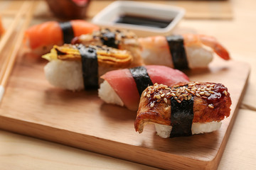 Board with tasty sushi on wooden table