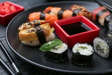Different tasty sushi with sauce on dark plate