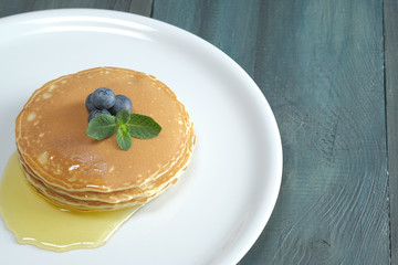 Pancake with blueberries, mint and honey on a white plate. Perfect breakfast