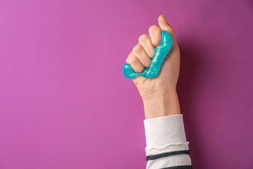 Female hand with anti-stress plasticine on color background