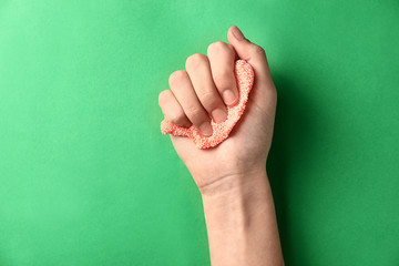 Female hand with anti-stress plasticine on color background