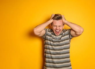 Portrait of screaming young man on color background
