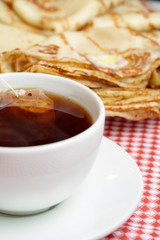 Fresh, tasty breakfast with pancakes and tea on a bright background.