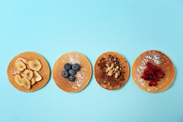Tasty pancakes with banana slices, berries and walnuts on color background