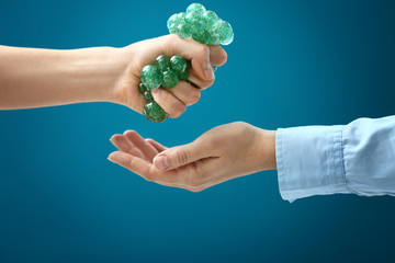 Woman giving her colleague stress ball on color background