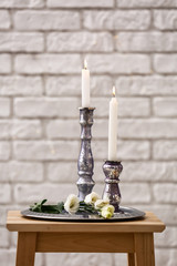 Holders with burning candles against brick wall