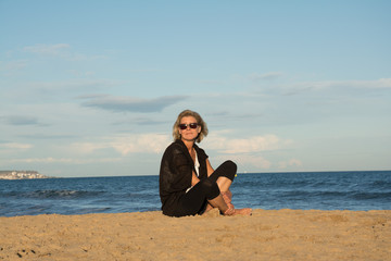 Fototapeta na wymiar Frau am Strand mit Sonnenbrille sitzend
