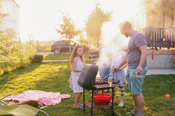 Picture of big happy family making barbeque in their backyard. Family time on sunny summer day.