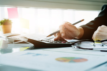 Close up Business woman using calculator and laptop for do math finance on wooden desk in office and business working background, tax, accounting, statistics and analytic research concept