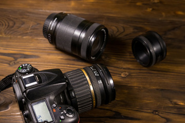 Fototapeta na wymiar Modern photo camera and photo lenses on wooden table