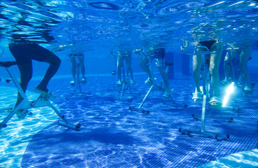 Touristen doing aqua aerobics on exercise bikes in swimming pool tropical hotel