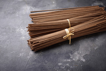 Raw uncooked Japanese soba noodles on grey bacground