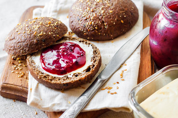 Homemade rye buns with linseeds, sesame and white poppy seeds served with butter and jam