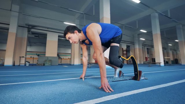 A man with a prosthetic leg start running in the gym
