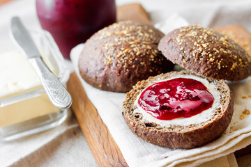 Homemade rye buns with linseeds, sesame and white poppy seeds served with butter and jam