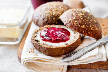 Homemade rye buns with linseeds, sesame and white poppy seeds served with butter and jam