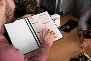 Young couple with menu sitting in restaurant