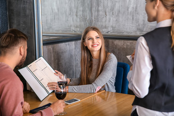Waitress taking and order from young couple in restaurant