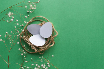 Easter nest wicker from rope with eggs cutted from white paper and branches of little gypsophila...