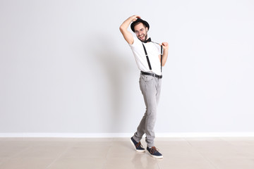 Handsome young man dancing near white wall