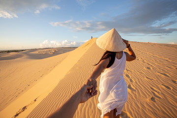 back view of Asian Woman travel with hat looking at White Sand dunes Mui ne, in Vietnam - obrazy, fototapety, plakaty