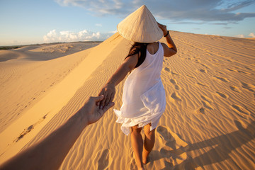 Fototapeta na wymiar back view of Asian Woman travel with hat looking at White Sand dunes Mui ne, in Vietnam