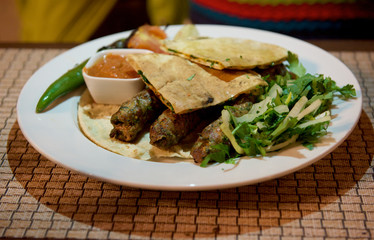 Kibbeh oriental restaurant beef, lamb, goat or camel meat served with fried green salad,pita, iolated.Travel to Middle East country Kingdom of Jordan - side view of plate with camel meat.Jordan food