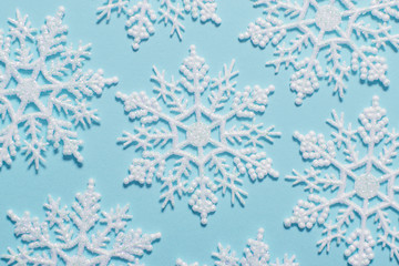 White glitter snowflake composition on a pastel blue background