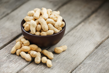 Peanuts in the shell, in a wooden cup on the table.