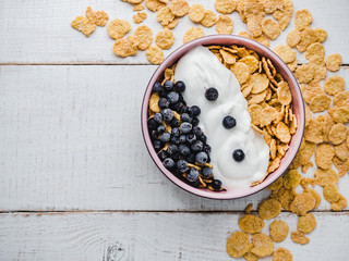 Healthy breakfast bowl, cornflakes, yogurt and fresh berries on a white boards. Close-up, top view, isolated background. Concept of healthy and tasty food
