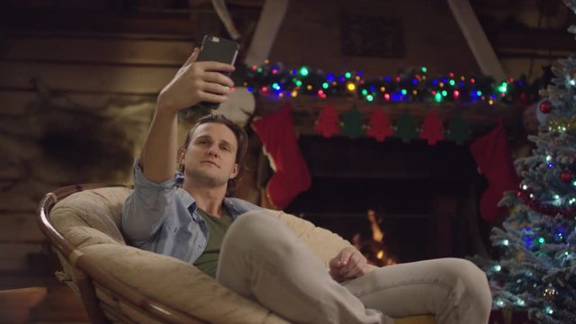 Long haired man takes selfshot on smartphone camera in Christmas night