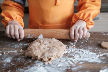 cute European boy in a suit of the cook makes ginger cookies