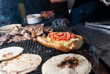 fast street food in the city of guatemala, bread with cabbage sausage, meat, sauces, roasted charcoal called Shuco.