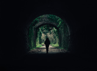 Chica en túnel de roca con un fondo natural verde, aire mágico y misterioso