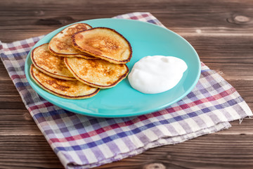 Stack of pancakes on a plate with sour cream. Traditional for the Russian pancake week. Rustic background