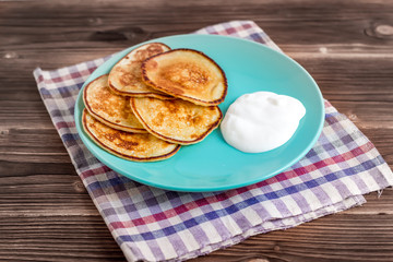 Stack of pancakes on a plate with sour cream. Traditional for the Russian pancake week. Rustic background