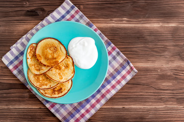 Stack of pancakes on a plate with sour cream. Traditional for the Russian pancake week. Rustic background