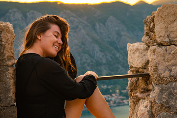 woman sitting on top of hill on sunset with beautiful view of kotor