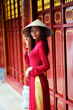 Vietnamese Woman in traditional Ao Dai dress and Non la conical hat