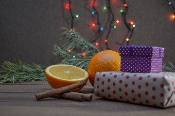 Boxes with gifts, oranges, cinnamon and Christmas tree - not a wooden background. Winter holiday card.