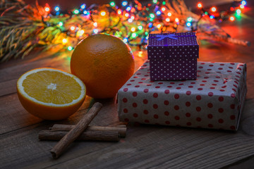 Beautiful Christmas lights on the background - in the foreground boxes with gifts, cinnamon, oranges. The aroma of the winter holidays.