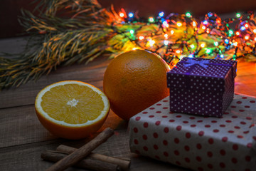 Beautiful Christmas lights on the background - in the foreground boxes with gifts, cinnamon, oranges. The aroma of the winter holidays.
