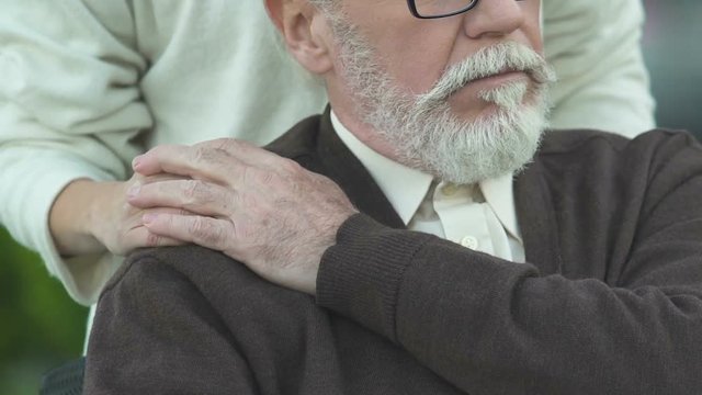 Daughter putting hand on old father shoulder, caring and supporting in sickness