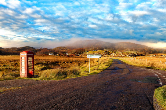 Autumn view of a red telephone box at the side of a quiet road in the remote misty Ardnamurchan moors of the Scottish Highlands
