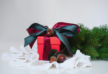 Red gift box with Christmas decorations  on white lace knitted napkin. Place for text.