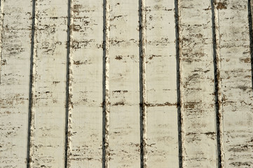 A white wall with a rough texture of a large industrial building with ribs and scuffs to the...