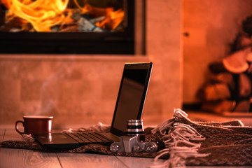 Laptop or notebook, camera, cup on the fireplace background. Concept of freelance or remote...